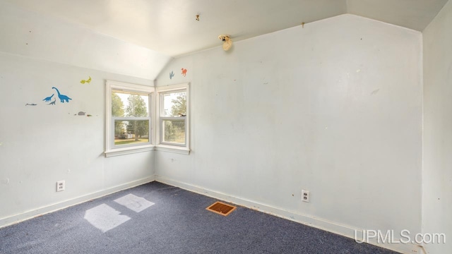 carpeted spare room featuring vaulted ceiling