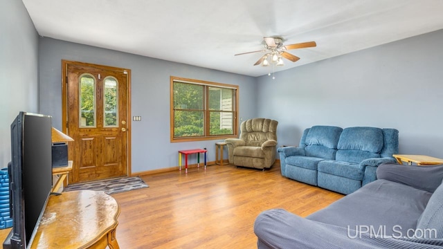 living area with light wood-style flooring, baseboards, and ceiling fan
