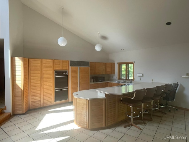 kitchen with high vaulted ceiling, kitchen peninsula, pendant lighting, double oven, and sink