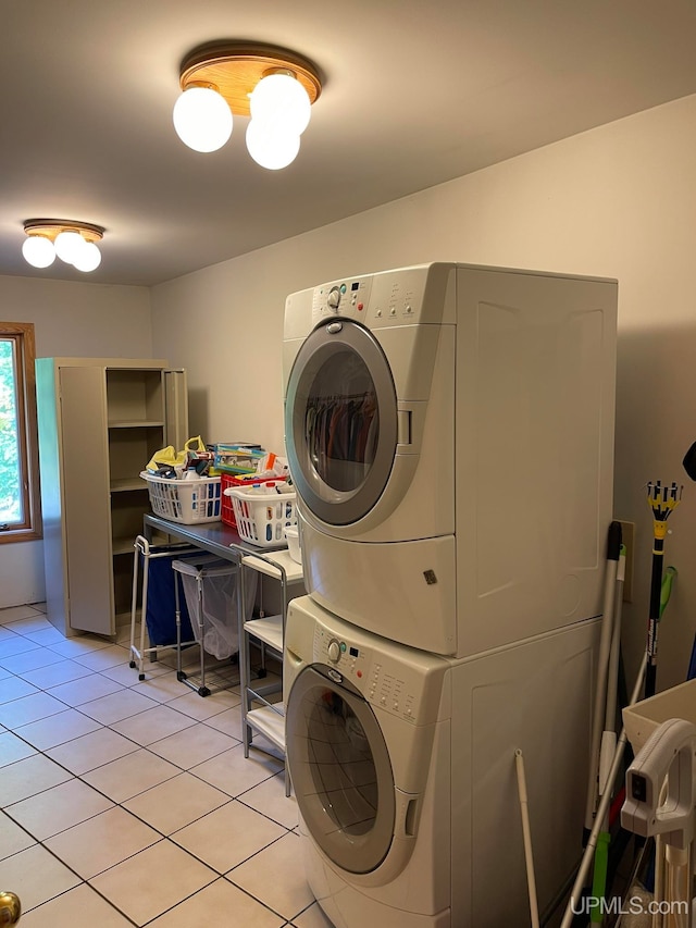 clothes washing area featuring light tile patterned flooring and stacked washer / drying machine