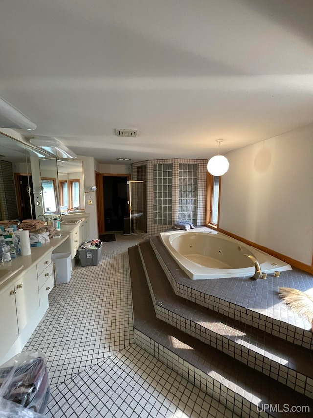 bathroom with tiled tub, vanity, and tile patterned flooring