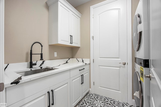 clothes washing area with cabinets, stacked washer / drying machine, and sink