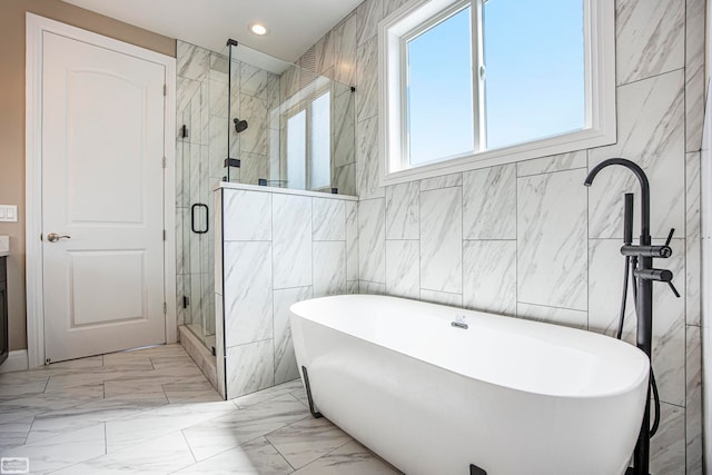 bathroom with shower with separate bathtub and tile walls