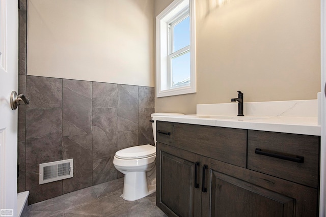 bathroom with tile walls, tile patterned flooring, vanity, and toilet