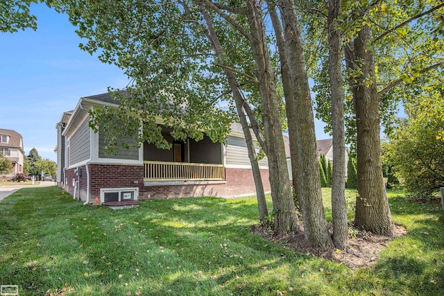 view of side of property with covered porch and a yard