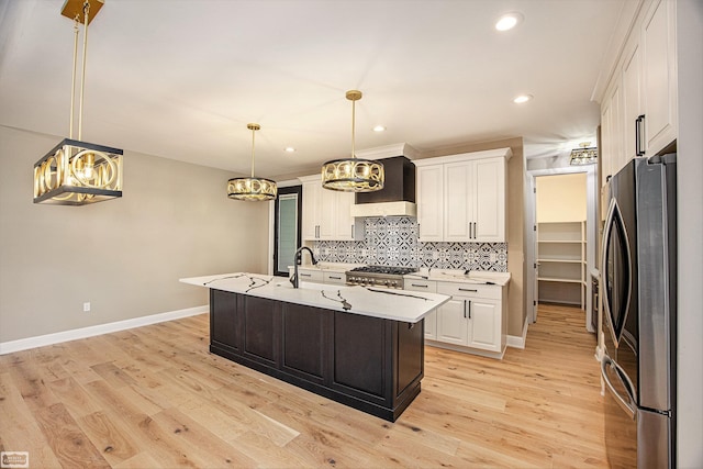 kitchen with premium range hood, a center island with sink, white cabinetry, stainless steel appliances, and light wood-type flooring