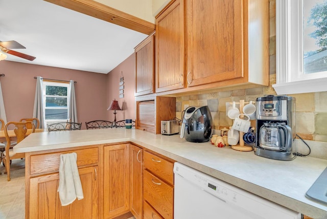 kitchen with white dishwasher, kitchen peninsula, ceiling fan, and tasteful backsplash