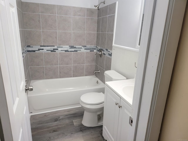 full bathroom featuring vanity, hardwood / wood-style flooring, tiled shower / bath combo, and toilet