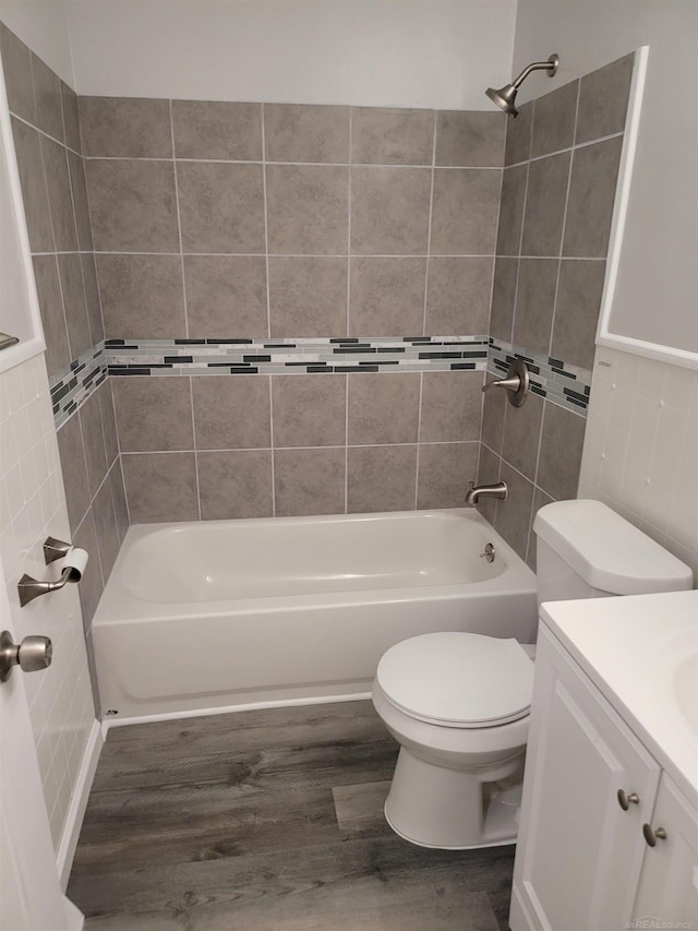 full bathroom with vanity, tiled shower / bath, hardwood / wood-style flooring, and toilet