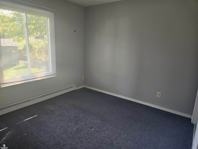 carpeted spare room with a baseboard heating unit