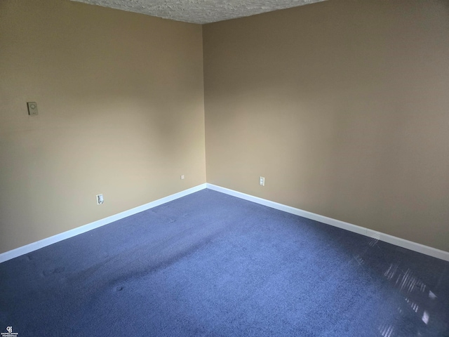 spare room featuring a textured ceiling and dark carpet