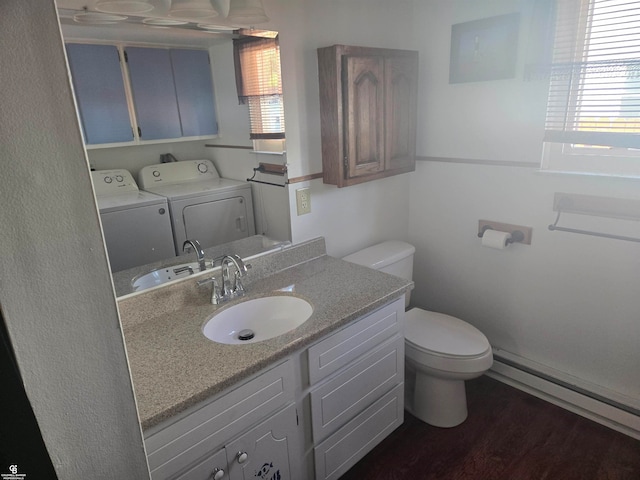 bathroom featuring vanity, baseboard heating, hardwood / wood-style flooring, washer and clothes dryer, and toilet