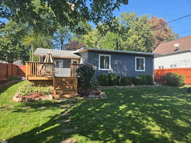 view of front facade featuring a wooden deck and a front yard