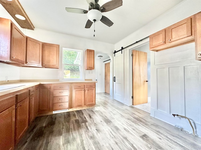 kitchen with ceiling fan, light hardwood / wood-style floors, and a barn door