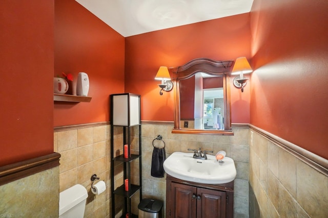 bathroom featuring vanity, tile walls, and toilet