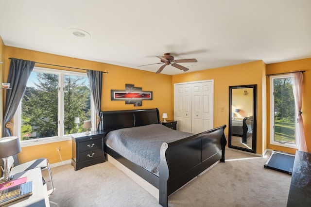 carpeted bedroom with ceiling fan, a closet, and multiple windows