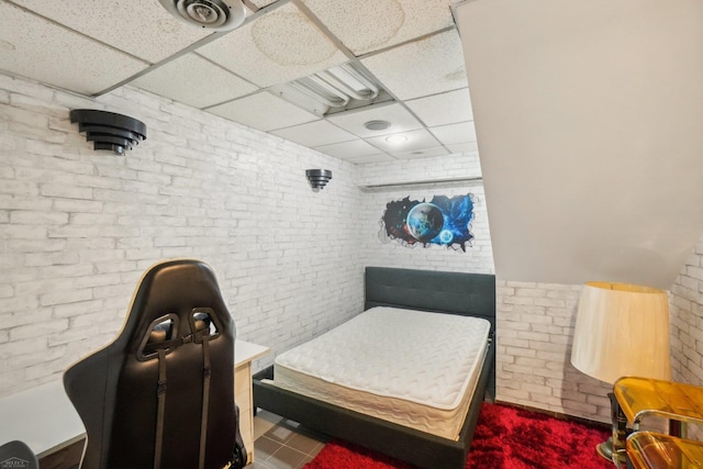 bedroom with brick wall and a drop ceiling