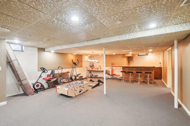 basement with carpet flooring, bar area, and a paneled ceiling