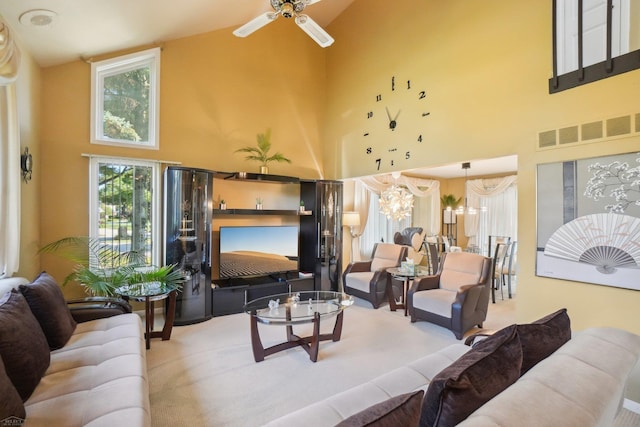 carpeted living room with ceiling fan with notable chandelier and high vaulted ceiling