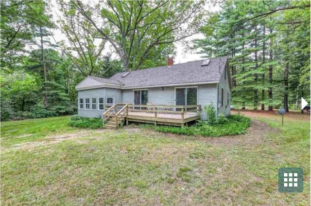 rear view of property with a deck and a yard