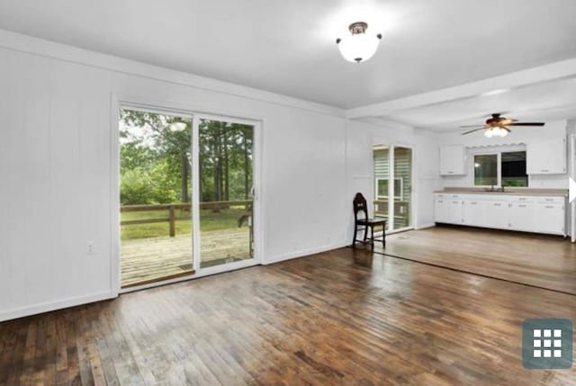 unfurnished living room with ceiling fan, dark wood-type flooring, and sink