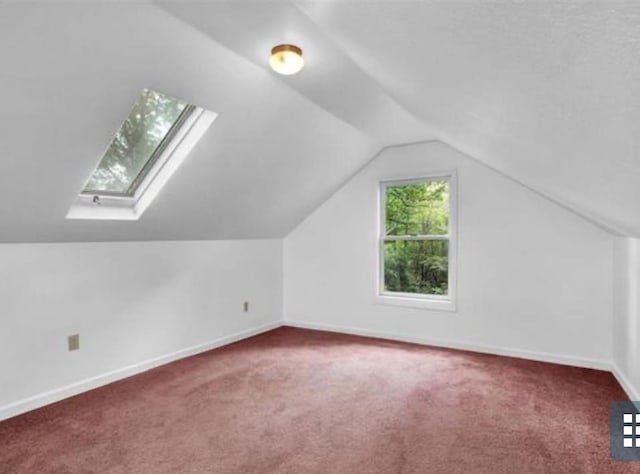 additional living space featuring carpet and vaulted ceiling with skylight