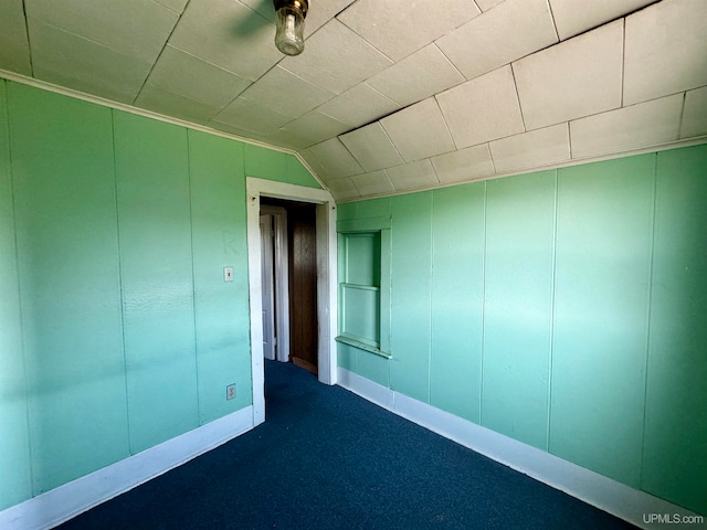 unfurnished room with lofted ceiling and dark colored carpet