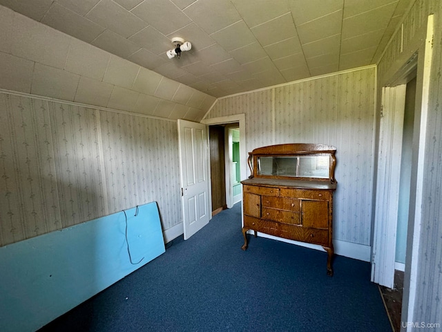 unfurnished bedroom with lofted ceiling and dark carpet