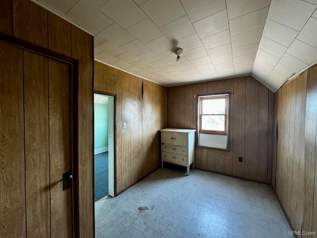 bonus room with lofted ceiling and wooden walls