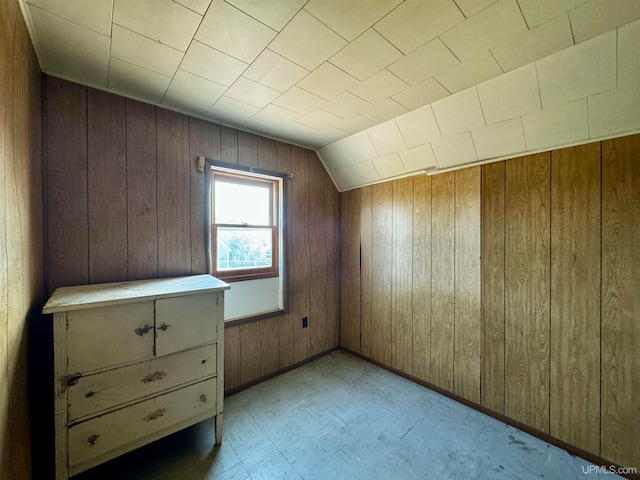 bonus room with wooden walls and vaulted ceiling