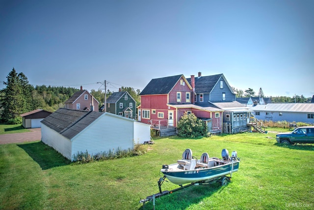 back of house featuring a lawn and an outdoor structure