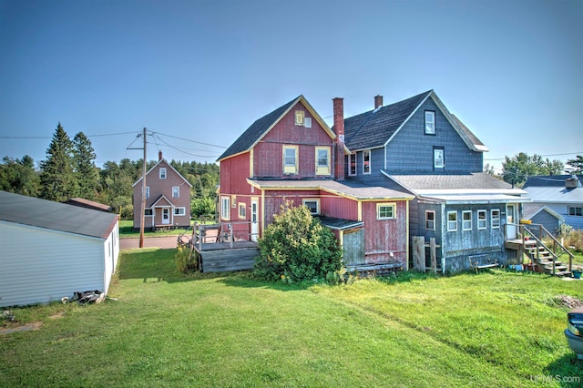 rear view of house featuring a wooden deck and a yard