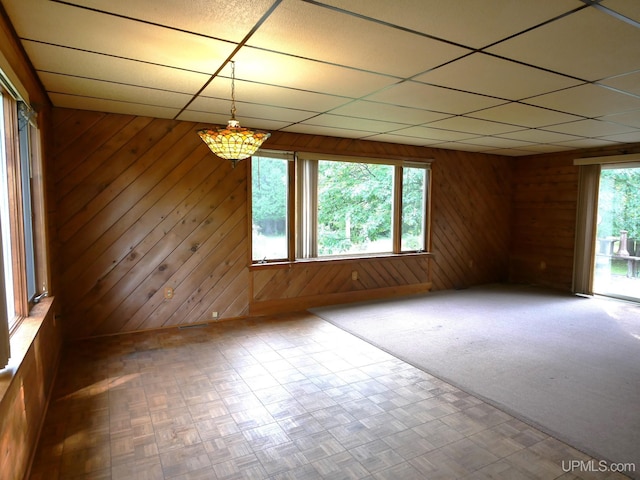 unfurnished room with wood walls, parquet floors, and a paneled ceiling