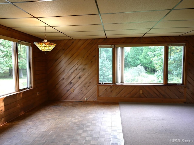 unfurnished room with a paneled ceiling and wooden walls