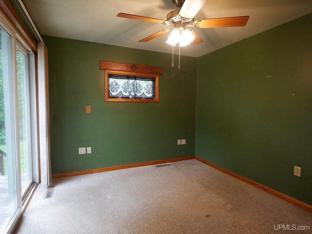 spare room featuring light carpet, ceiling fan, and a wealth of natural light