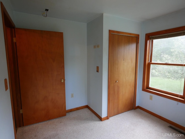 unfurnished bedroom with light carpet and a closet