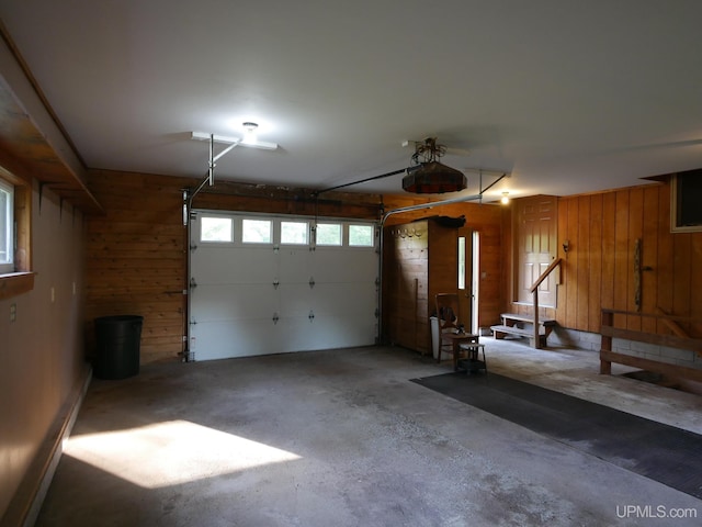 garage featuring a garage door opener and wooden walls