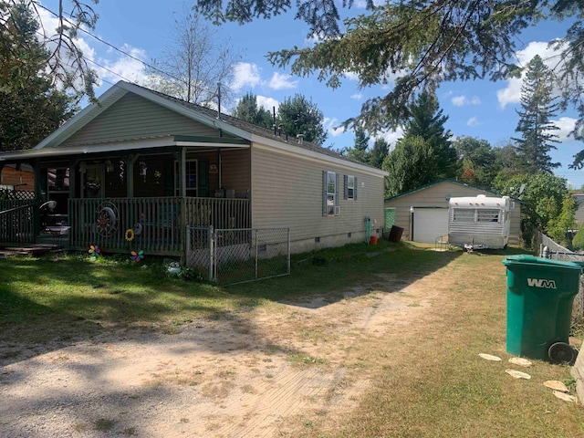 back of house featuring a garage, a lawn, and an outbuilding