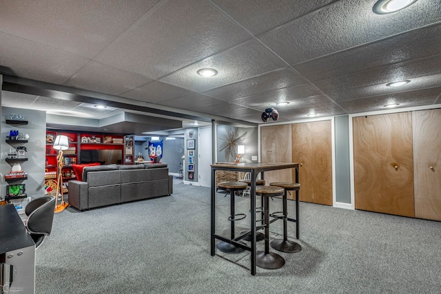 basement with a paneled ceiling and carpet