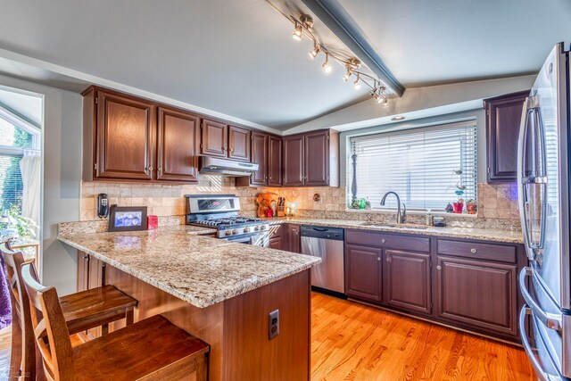 kitchen with appliances with stainless steel finishes, sink, decorative backsplash, and a breakfast bar