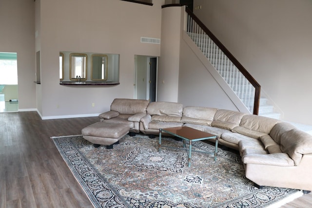 living room featuring a towering ceiling and hardwood / wood-style flooring