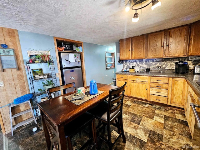 kitchen with a textured ceiling, stainless steel fridge, and decorative backsplash