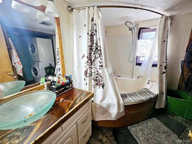 bathroom featuring stacked washing maching and dryer, shower / bathtub combination with curtain, and vanity