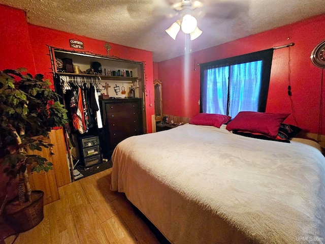 bedroom featuring a textured ceiling, wood-type flooring, ceiling fan, and a closet