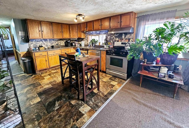 kitchen featuring a textured ceiling, appliances with stainless steel finishes, and backsplash