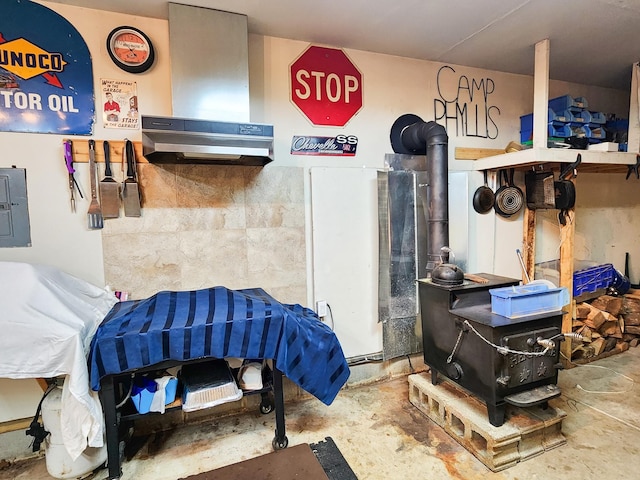 miscellaneous room with a wood stove, concrete flooring, and electric panel