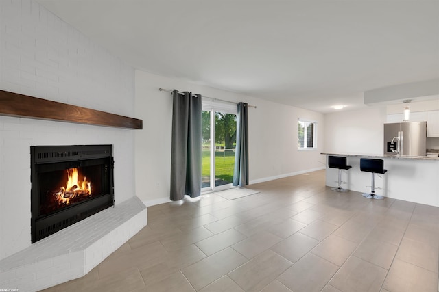 unfurnished living room with a brick fireplace and light tile patterned floors