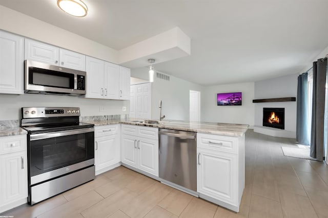 kitchen featuring sink, kitchen peninsula, white cabinetry, appliances with stainless steel finishes, and light stone countertops