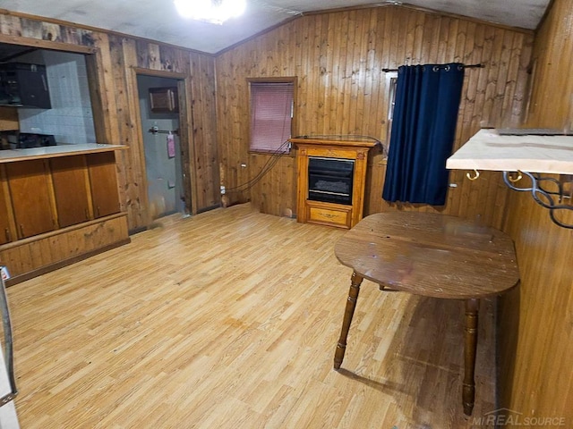 interior space featuring light hardwood / wood-style floors, wood walls, and vaulted ceiling