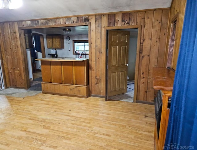 interior space featuring light hardwood / wood-style floors, wood walls, and kitchen peninsula